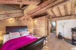 Experience rustic charm in this stunning bedroom featuring exposed wooden beams and paneling.