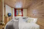 Experience rustic charm in this cozy bedroom, featuring warm wooden walls and ceiling.