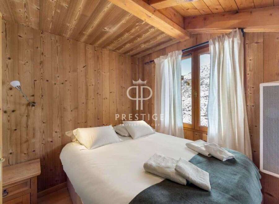 Experience the charm of this cozy bedroom, featuring warm wooden walls and a rustic ceiling.