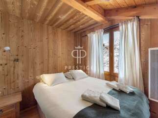 Experience the charm of this cozy bedroom, featuring warm wooden walls and a rustic ceiling.