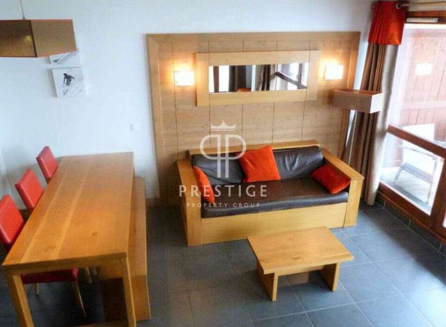 Discover a cozy living space with a stylish wooden dining table and vibrant red chairs.