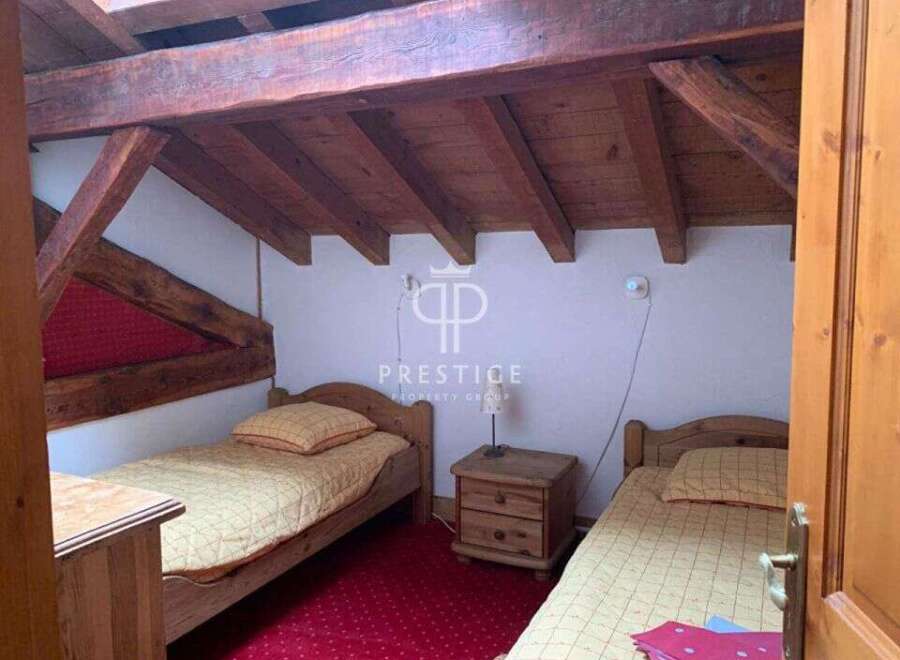 Discover a charming bedroom with rustic wooden beams and cozy single beds.