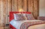 Experience luxury in this stunning bedroom featuring a vibrant red headboard and a cozy, patterned bedspread.