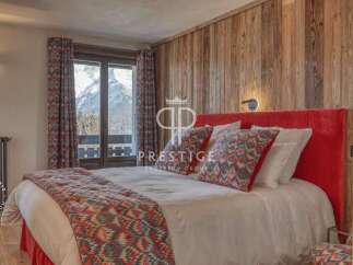 Experience luxury in this stunning bedroom featuring a cozy bed with vibrant pillows and a plush red headboard.