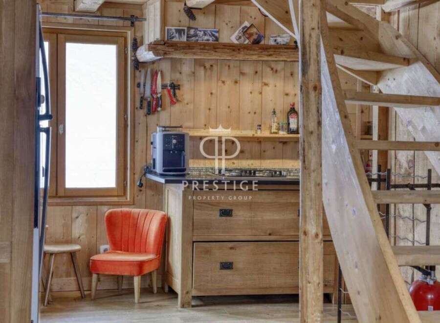 Discover rustic charm in this cozy cabin! Featuring a well-equipped kitchen with wooden cabinetry and a stylish orange chair, this space is perfect for relaxation.