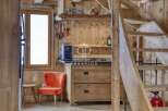 Discover rustic charm in this cozy cabin! Featuring a well-equipped kitchen with wooden cabinetry and a stylish orange chair, this space is perfect for relaxation.