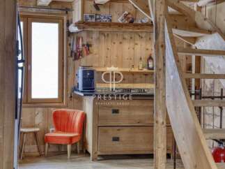 Discover rustic charm in this cozy cabin! Featuring a well-equipped kitchen with wooden cabinetry and a stylish orange chair, this space is perfect for relaxation.