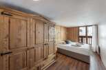 Discover a cozy bedroom retreat featuring a stunning wooden wardrobe and warm wooden paneling.