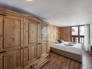 Discover a cozy bedroom retreat featuring a stunning wooden wardrobe and warm wooden paneling.