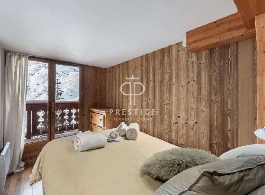 Cozy bedroom with wooden paneling and a balcony overlooking a snowy landscape.