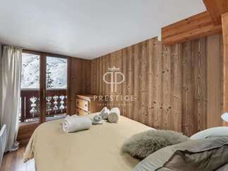 Cozy bedroom with wooden paneling and a balcony overlooking a snowy landscape.