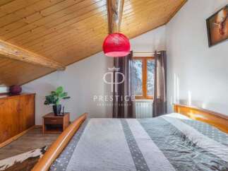 Discover the charm of this cozy bedroom, featuring a unique sloped wooden ceiling and a warm, inviting atmosphere.