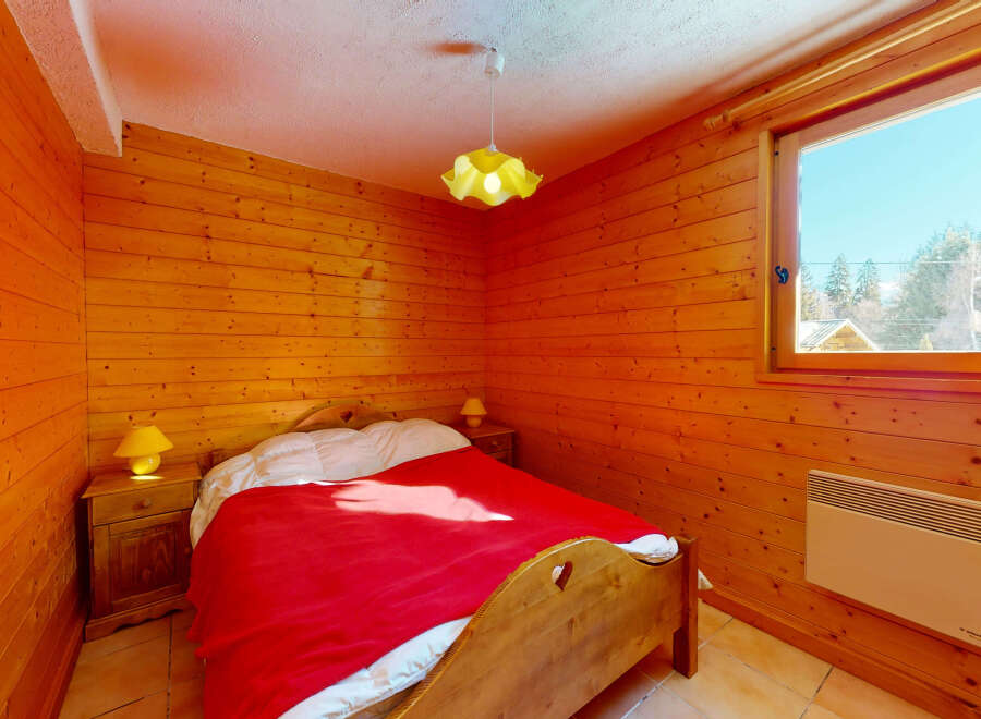 Cozy bedroom with wooden walls and a warm ambiance.