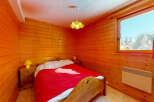 Cozy bedroom with wooden walls and a warm ambiance.