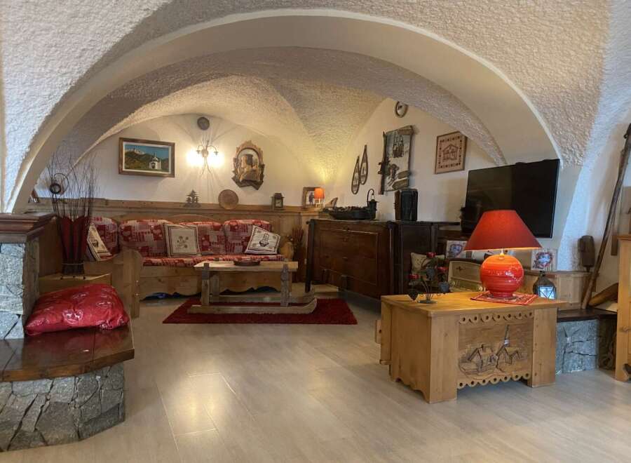 Charming chalet living room with vaulted ceilings, rustic wooden furniture, and a cozy fireplace.
