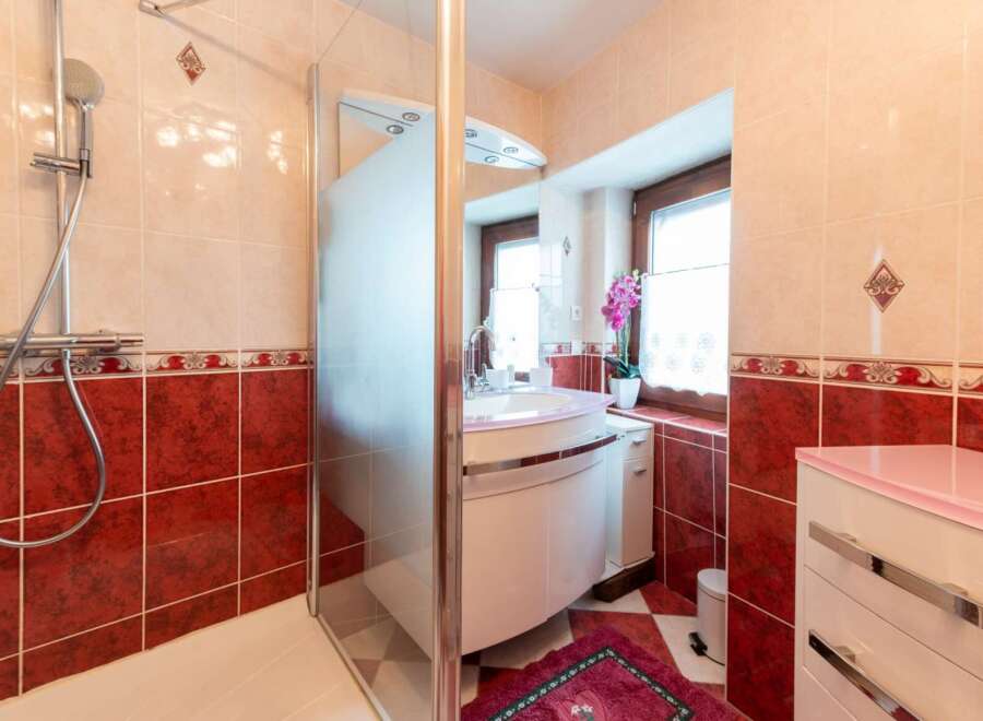 This charming bathroom boasts a modern shower with glass enclosure and a stylish pink vanity with a curved countertop.