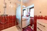 This charming bathroom boasts a modern shower with glass enclosure and a stylish pink vanity with a curved countertop.