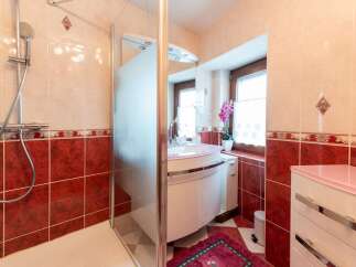 This charming bathroom boasts a modern shower with glass enclosure and a stylish pink vanity with a curved countertop.