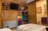 Cozy chalet bedroom with twin beds, featuring a rustic wood wall and built-in storage.