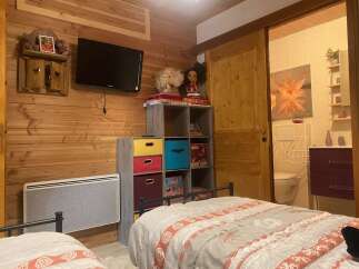 Cozy chalet bedroom with twin beds, featuring a rustic wood wall and built-in storage.
