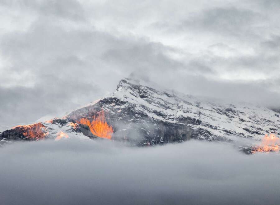 Witness the majestic beauty of a snow-capped mountain peak, kissed by the golden hues of the setting sun.