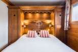 Discover the charm of this cozy bedroom, featuring a custom-built wooden headboard and matching wardrobes.