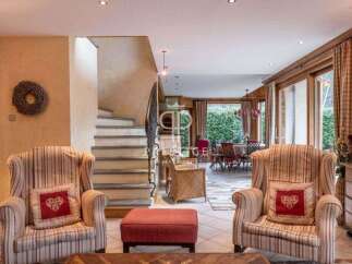 Discover the charm of this exquisite property, featuring a cozy living area with inviting armchairs and a stylish ottoman.