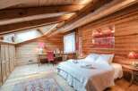Experience rustic charm in this cozy bedroom, featuring warm wooden walls and a sloped ceiling.