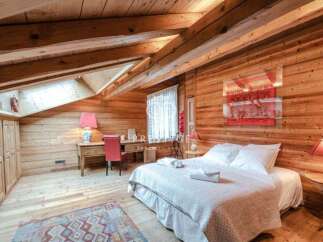 Experience rustic charm in this cozy bedroom, featuring warm wooden walls and a sloped ceiling.