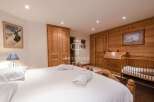 Discover the charm of this cozy bedroom, featuring a warm wooden interior and a comfortable bed.