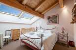 Discover a charming bedroom with a unique architectural design, featuring a skylight that floods the space with natural light.