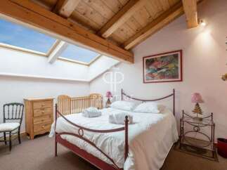 Discover a charming bedroom with a unique architectural design, featuring a skylight that floods the space with natural light.