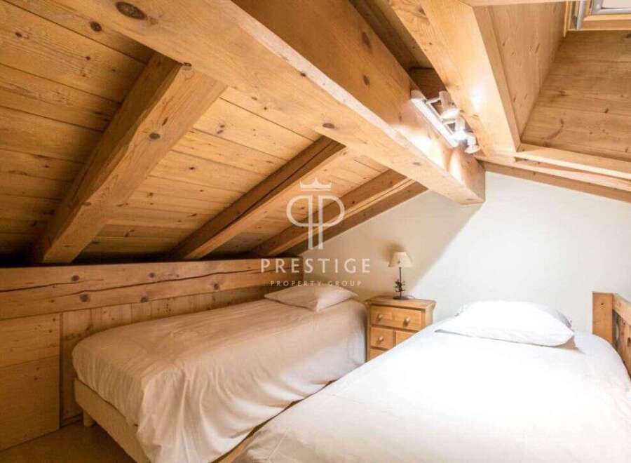 Discover the charm of this cozy bedroom featuring exposed wooden beams and a unique sloped ceiling.