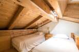 Discover the charm of this cozy bedroom featuring exposed wooden beams and a unique sloped ceiling.