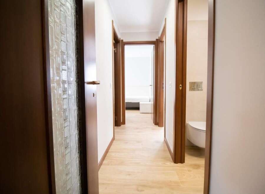Explore this inviting hallway with its warm wooden doors and light-filled ambiance.