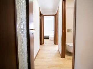 Explore this inviting hallway with its warm wooden doors and light-filled ambiance.