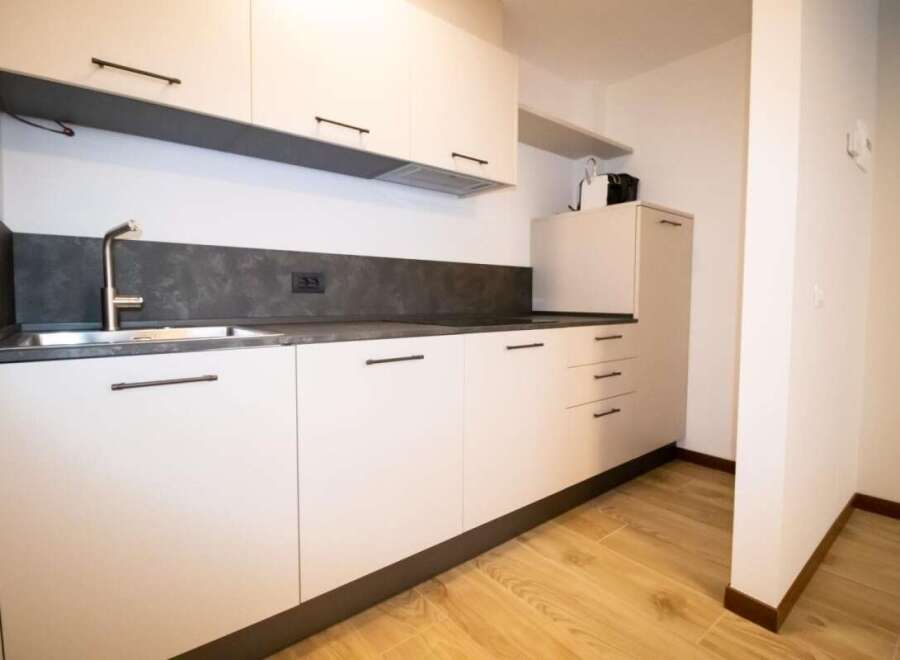 Modern kitchen with sleek white cabinets and dark countertops.