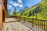 Experience breathtaking mountain views from the expansive stone patio of this charming wooden cabin.