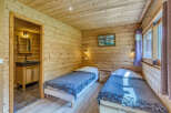 Experience rustic charm in this cozy wooden cabin bedroom, featuring two comfortable twin beds adorned with plush grey blankets.