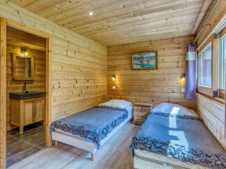 Experience rustic charm in this cozy wooden cabin bedroom, featuring two comfortable twin beds adorned with plush grey blankets.