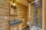 Experience rustic charm in this bathroom, featuring warm wooden walls and a modern stone sink.