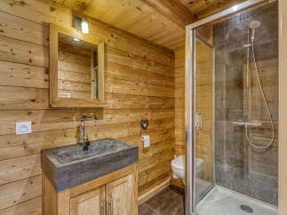 Experience rustic charm in this bathroom, featuring warm wooden walls and a modern stone sink.