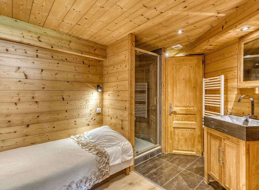 Experience rustic charm in this cozy bedroom featuring warm wooden walls and ceiling.