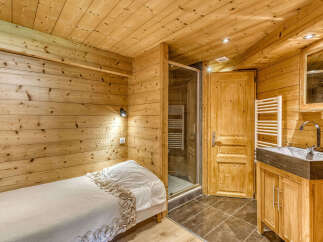 Experience rustic charm in this cozy bedroom featuring warm wooden walls and ceiling.