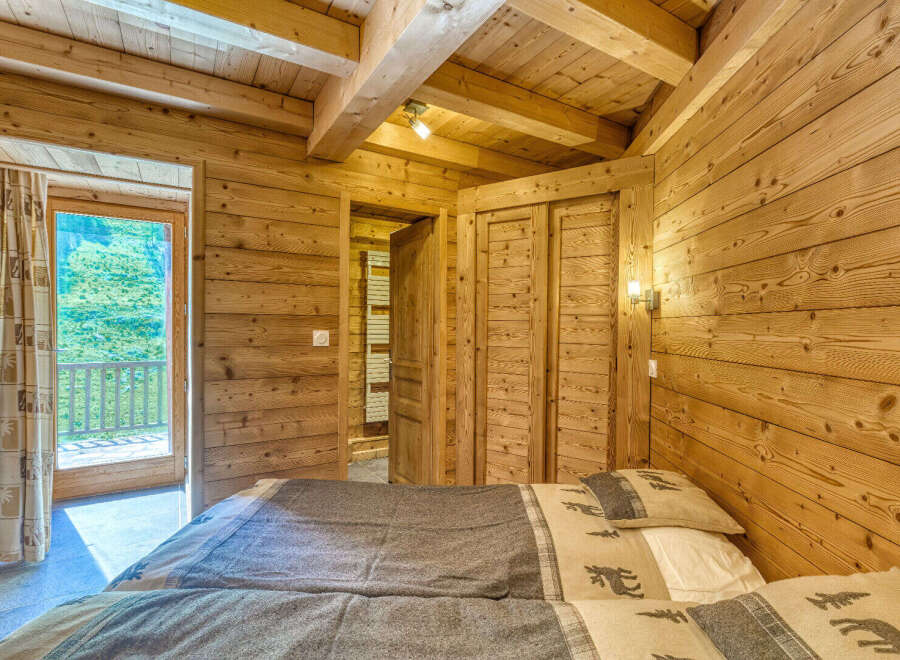 Experience rustic charm in this cozy wooden bedroom, featuring two comfortable beds adorned with nature-themed linens.