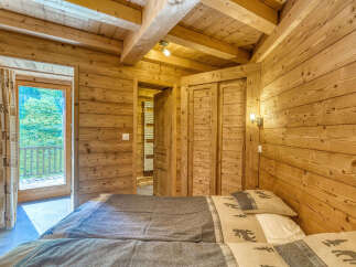 Experience rustic charm in this cozy wooden bedroom, featuring two comfortable beds adorned with nature-themed linens.