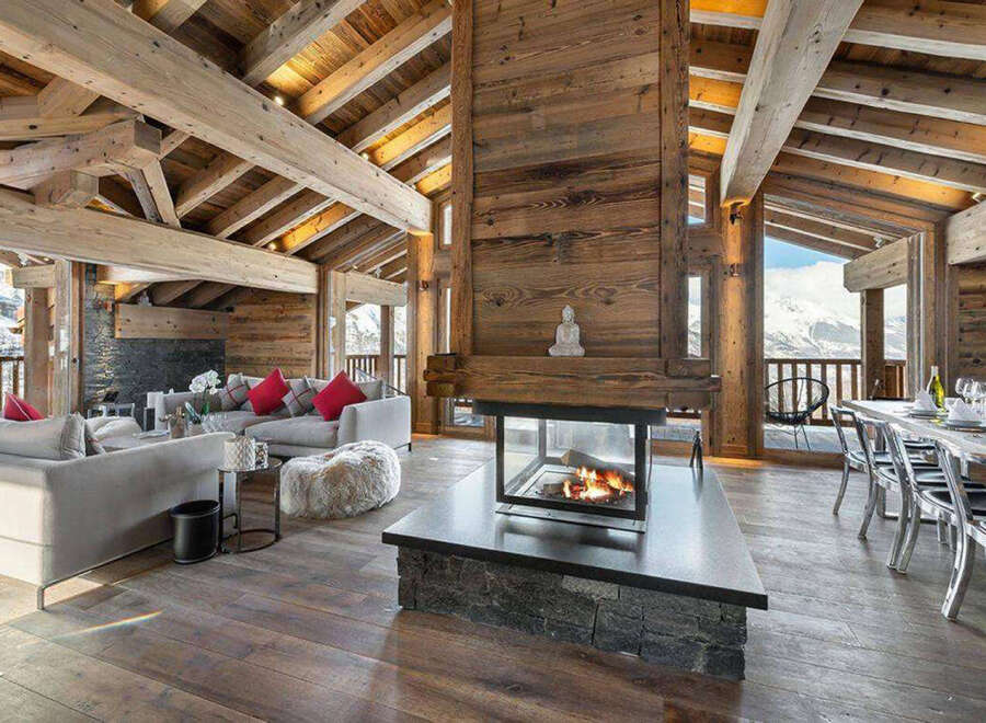 Experience luxury living in this stunning chalet, featuring a cozy fireplace and exposed wooden beams.