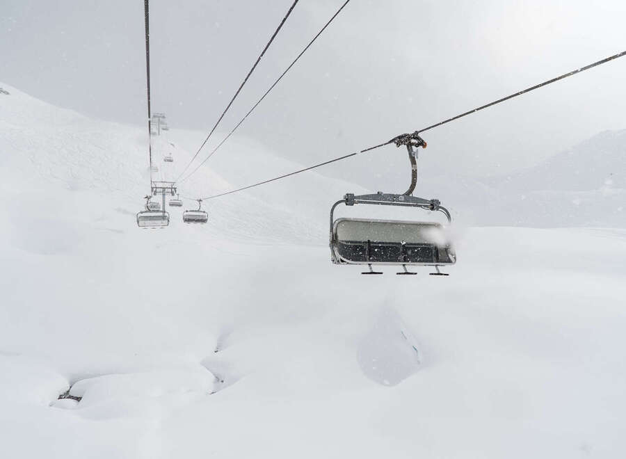 Experience the thrill of skiing with this stunning image of a ski lift amidst a snowy landscape.