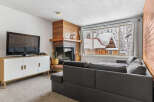 Cozy up in this charming living room with a fireplace and a stunning view of the snowy landscape.