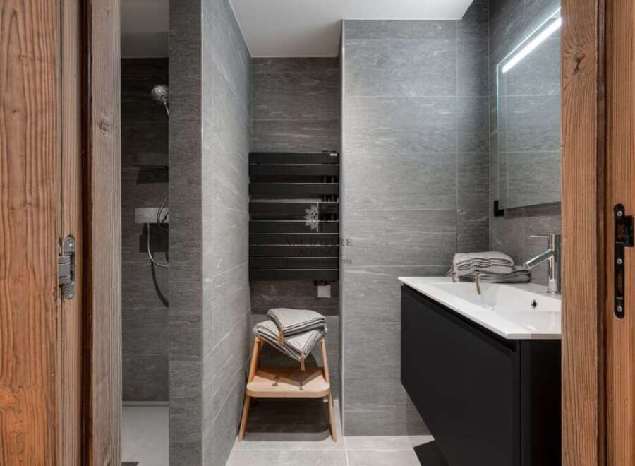 Modern bathroom with gray tile, a walk-in shower, and a floating vanity with a sleek black finish.